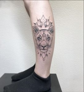 Tatuagem feminina de leão na panturrilha