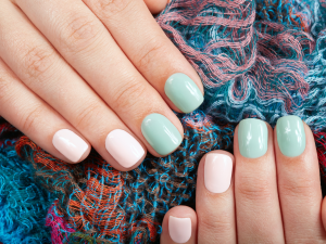 Tendências de unhas curtas. Foto tem mãos com unhas curtas e coloridas com branco e verde claro.