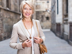 Peças de roupas que combinam com mulheres de 50 anos. Foto mulher branca e loira com blazer bege e camiseta branca.