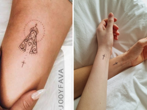 Tatuagem minimalista no braço e no pulso, sendo uma com a imagem de uma nossa senhora aparecida e outra com a imagem de uma cruz