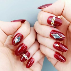 unhas vermelhas com pedras em destaque