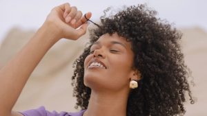mulher mexendo em cacho de seu cabelo crespo
