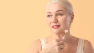 mulher madura fazendo massagem facial com equipamento